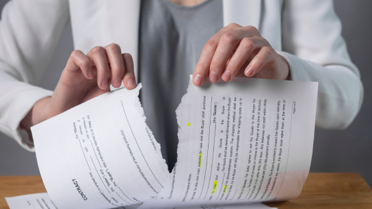 Torn contract in hands. Terminated agreement concept. Ripping paper document and breaching rules.